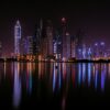 A city skyline at night reflected in the water