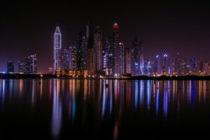 A city skyline at night reflected in the water